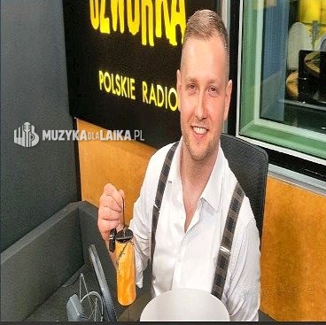 Michał Drezner uśmiechnięty w fotelu studia Czwórki, w tle podświetlony napis Czwórka Polskie Radio