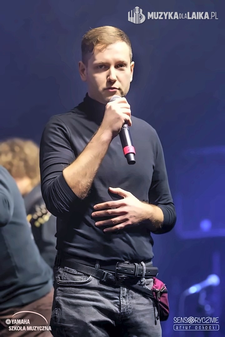 Michał Drezner na scenie z mikrofonem