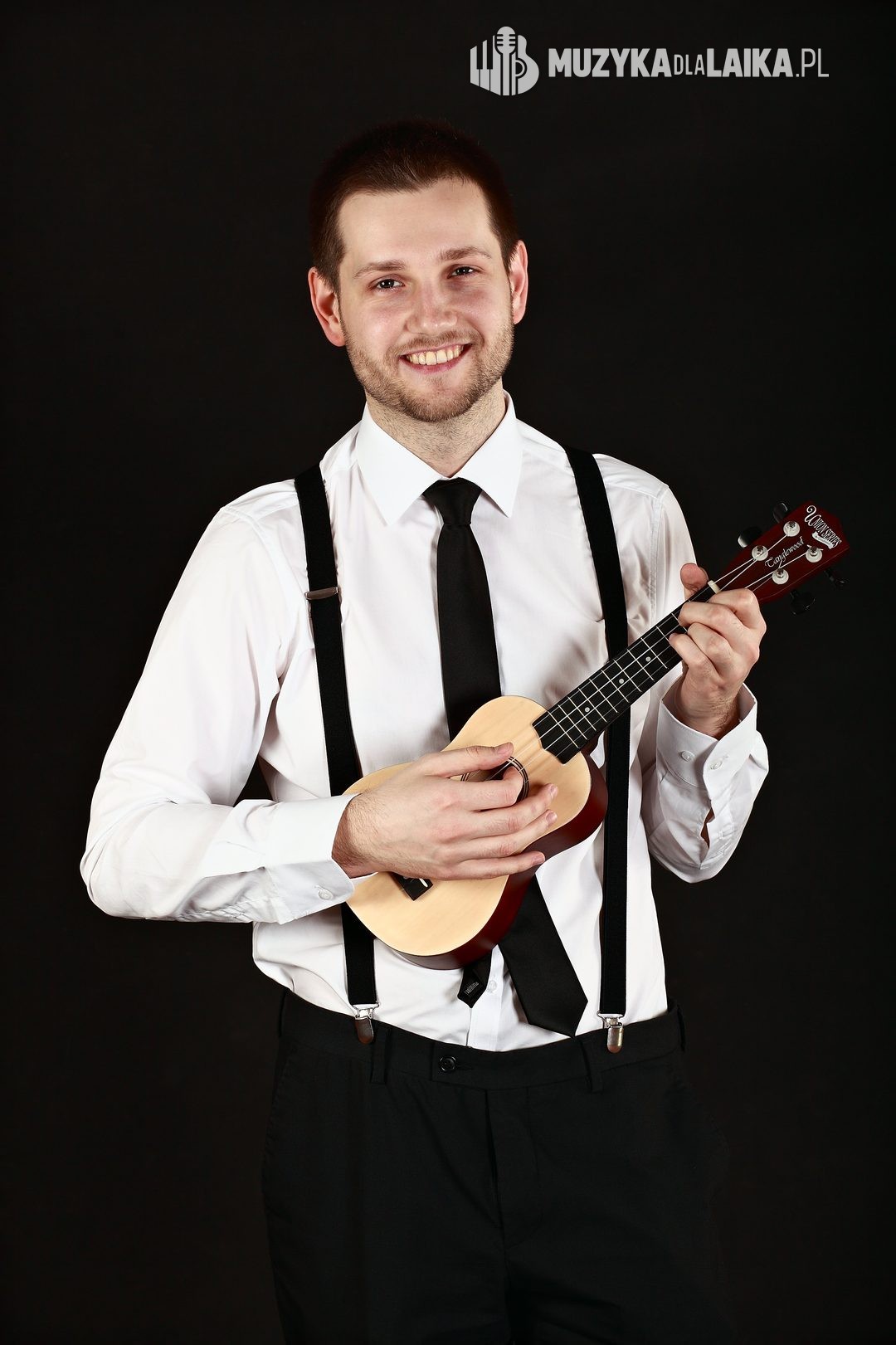 Michał gra na ukulele w studiu, na czarnym tle