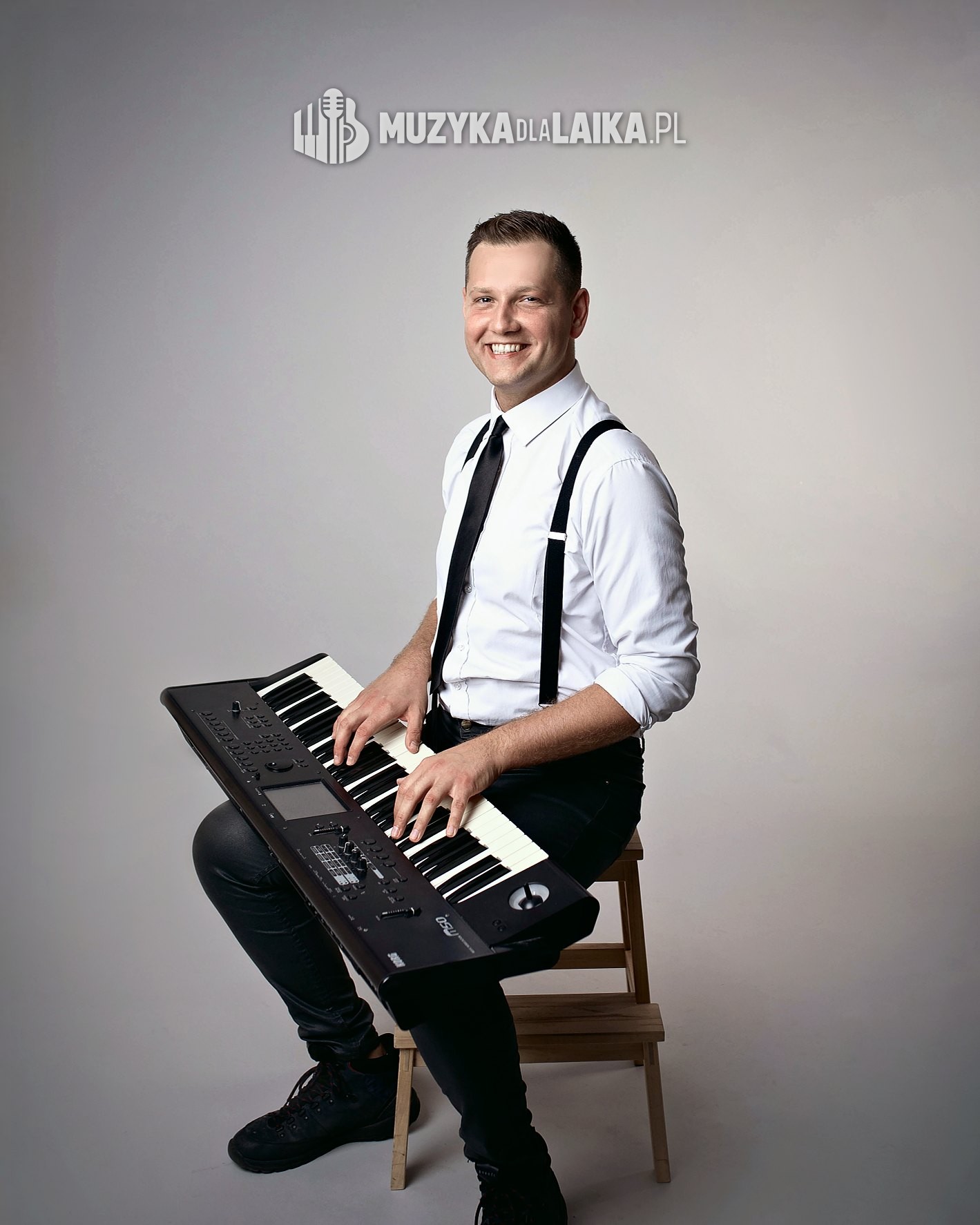 Michał Drezner siedzi z&nbsp;keyboardem na&nbsp;kolanach, dłonie na&nbsp;klawiszach