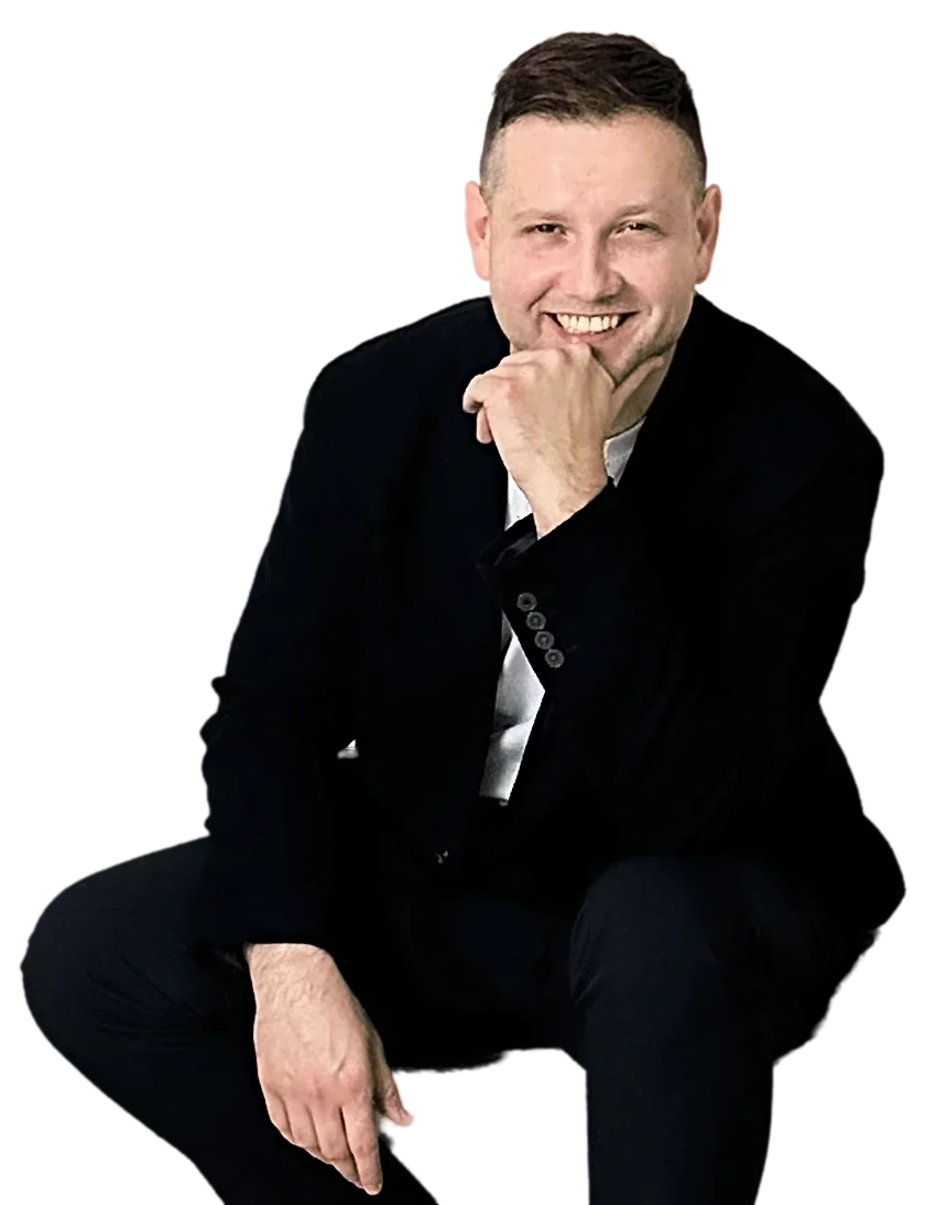 Michał Drezner w ciemnej marynarce, uśmiechnięty, z dłonią przy brodzie
