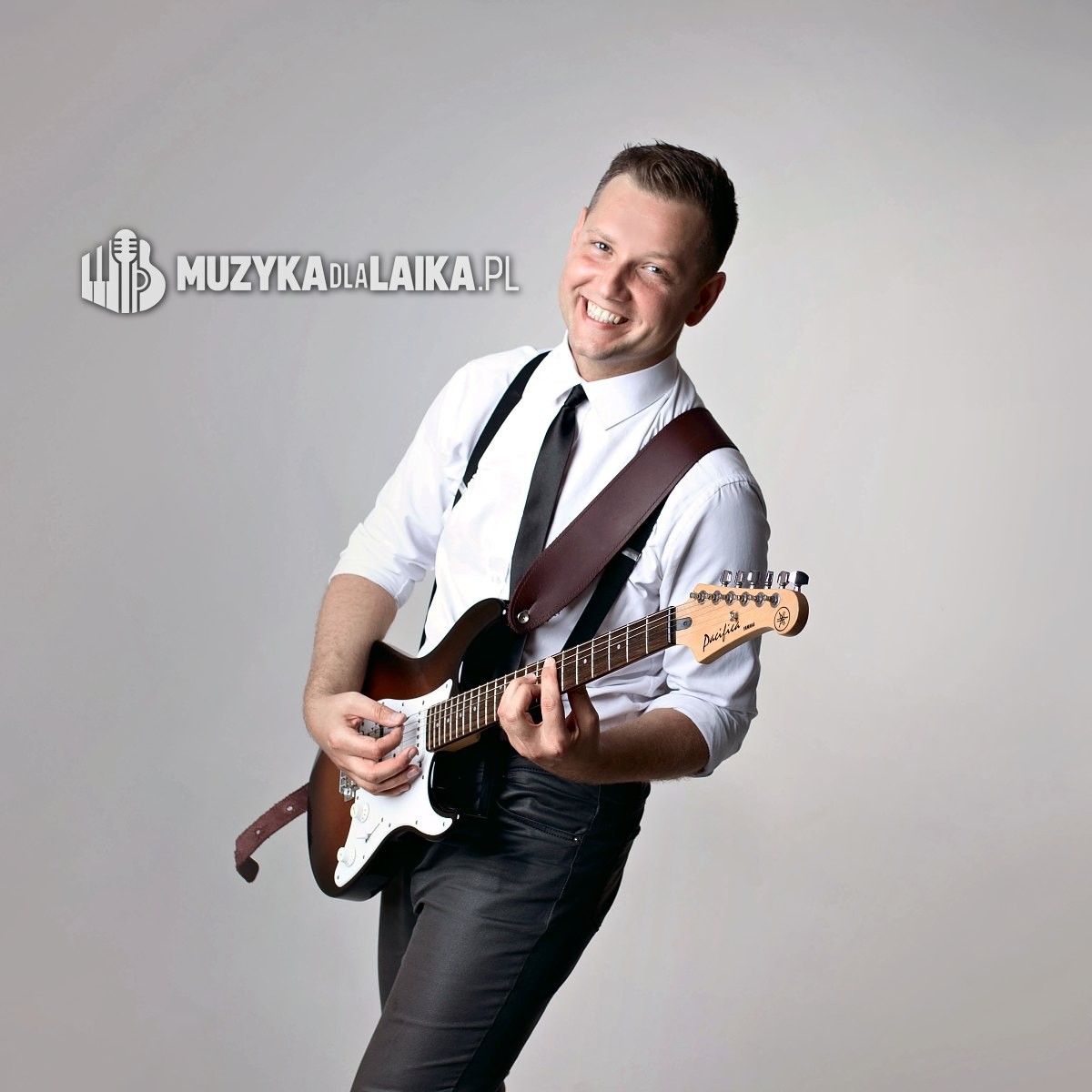 Michał Drezner z gitarą elektryczną, uśmiechnięty