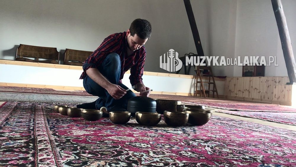 Michał Drezner przy misach dźwiękowych rozłożonych na dywanie